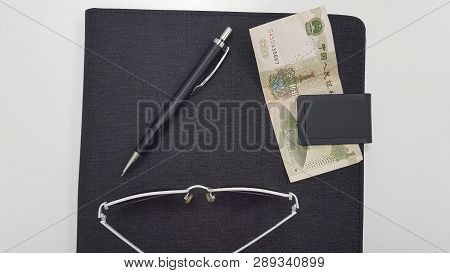 White Fashionable Sunglasses Black Pen And One Chinese Money Banknote On Black Folder