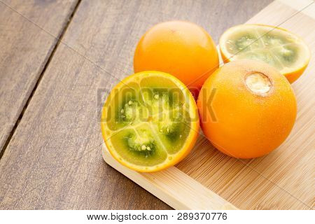Fruits And Slices Of Lulo Or Naranjilla On The Wooden Table - Solanum Quitoense