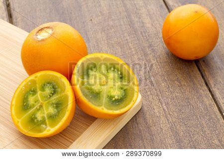 Fruits And Slices Of Lulo Or Naranjilla On The Wooden Table - Solanum Quitoense