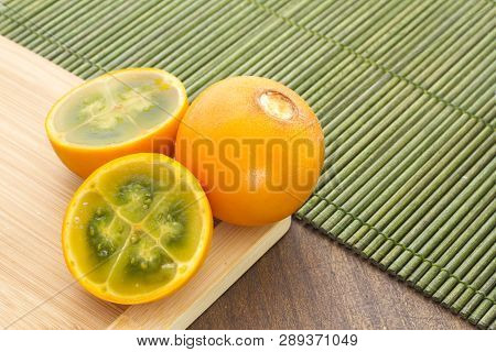 Fruits And Slices Of Lulo Or Naranjilla On The Wooden Table - Solanum Quitoense