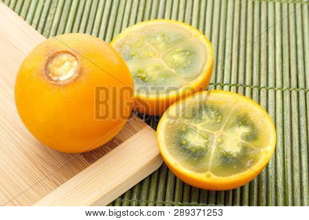 Fruits And Slices Of Lulo Or Naranjilla On The Wooden Table - Solanum Quitoense