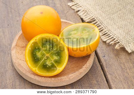 Fruits And Slices Of Lulo Or Naranjilla On The Wooden Table - Solanum Quitoense