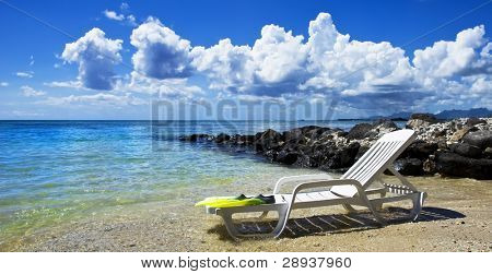 en strandstol och dykutrustning på en tropisk ö strand med vacker himmel och moln - fokus på