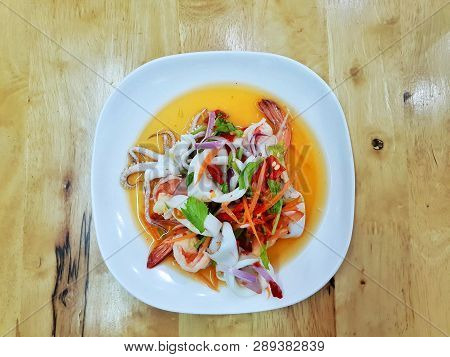 Thai Food Style, Top View Of Spicy Thai Seafood Salad On White Plate On Wooden Table In Restaurant, 