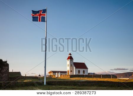 Fluttering Icelandic flag near  white church at Modrudalur farm, the highest inhabited settlement in Iceland, NorÃ°ur-MÃºlasÃ½sla, Eastern Iceland, Scandinavia