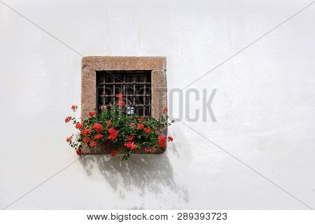 Stone Window With Iron Grates And Red Geranium Flower