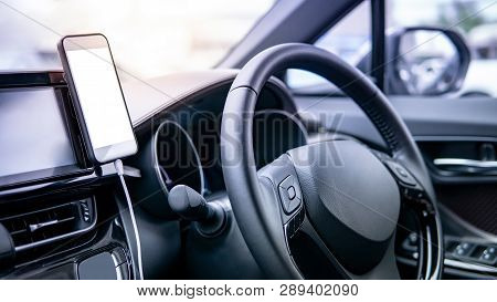 Smartphone With White Blank Screen Mounting With Magnet On The Car Console Near Steering Wheel. Usin