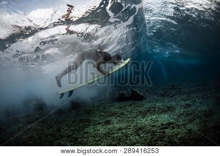 MALDIVES / HIMMAFUSHI - 10 MARCH 2019: Male surfer dives under the wave with surfboard