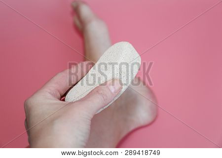 Pumice Stone For Foot Care. In The Photo A Woman Hand Holds A Pumice Near The Heel Of Her Foot. Remo