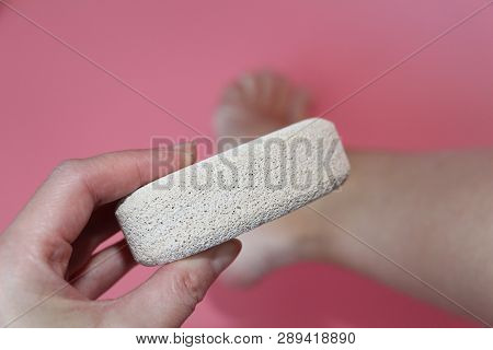 Pumice Stone For Foot Care. In The Photo A Woman Hand Holds A Pumice Near The Heel Of Her Foot. Remo