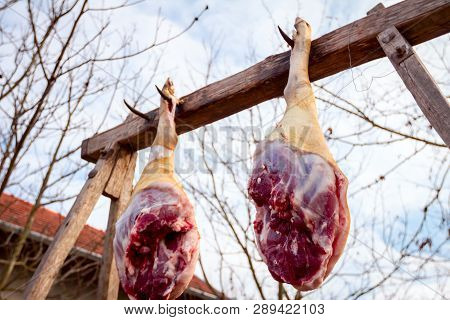 Raw Pork Hams Are Hanging On The Wooden Beam.