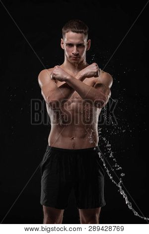 Wet Young Man Crossed His Fists, Standing In A Belligerent Pose With Water Splashes