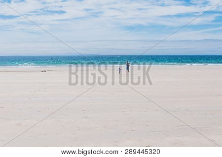 Father And Son Running Towards The Atlantic Ocean On The Beach In Finistere France