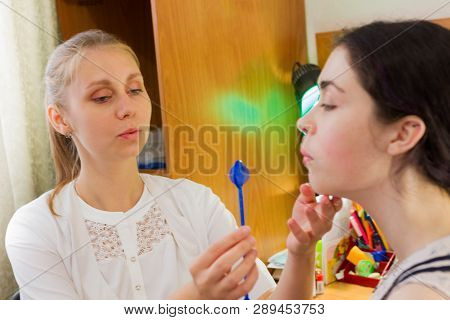 Young Woman Trains With Speech Therapy Probe In Soft Focus.