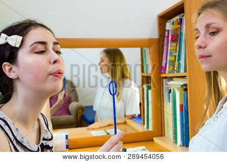 Young Woman Trains With Speech Therapy Probe In Soft Focus.