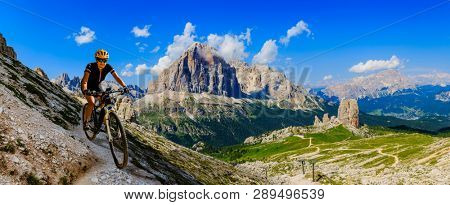 Cycling woman  riding on e-bike in Dolomites mountains landscape. Couple cycling MTB enduro trail track. Outdoor sport activity.