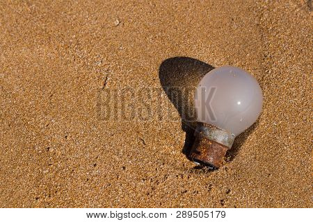 Enlightened Old Rusted Bulb With Its Shadow, Found On The Sand Of A Beach. Part Of The Set Beach Dis