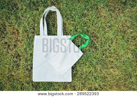 White Tote Canvas Fabric Eco Bag Cloth Shopping Sack On Green Grass Background / Zero Waste Use Less