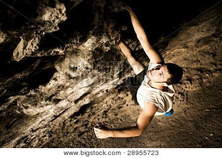 Giovani fanno scalatore facendo una parete di roccia in una grotta.
