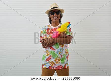 Happy Elderly Traveler Asian Man Wearing Summer T-shirt, Straw Hat And Sunglasses Holding Colorful S