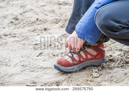 Hands Of A Little Girl Lace Up Their Shoes During A Hike In The Sand