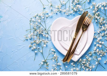 Plates In Form Of Hearts, Golden Knife And Fork And  Fresh White Gypsofila  Flowers On Blue Textured