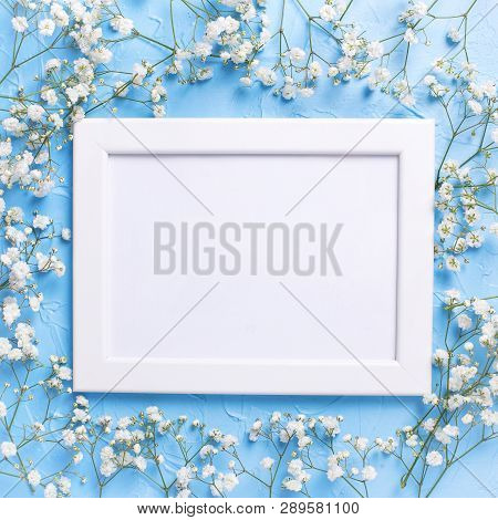 Empty  White Frame And  Fresh White Gypsofila  Flowers On Blue Textured Background. Top View. Flat L