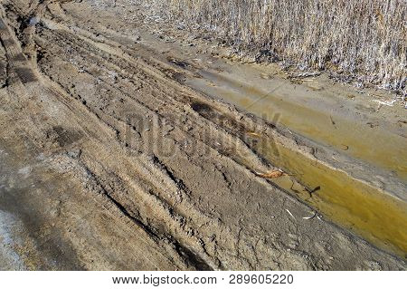 Off-piste. Deep Rubber Tracks On The Road Is Covered With Wet Dirty Sand, Off-road. Traces Of Tires