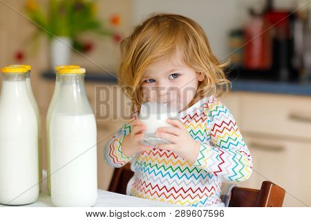 Adorable Toddler Girl Drinking Cow Milk For Breakfast. Cute Baby Daughter With Lots Of Bottles. Heal