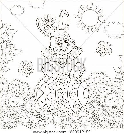 Little Easter Bunny Sitting On A Colorfully Decorated Big Egg Among Flowers And Flittering Butterfli