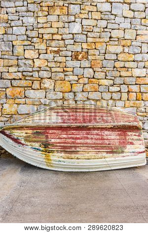 Old, Demolished Small Fishing Boat Against Stone Brick Made Wall. Fishery Obejcts.