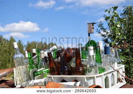 Empty Colored Bottles In Box With Sky Background
