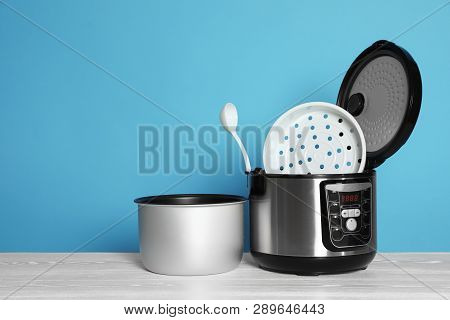 Disassembled Electric Multi Cooker With Spoon On Table Against Color Background. Space For Text