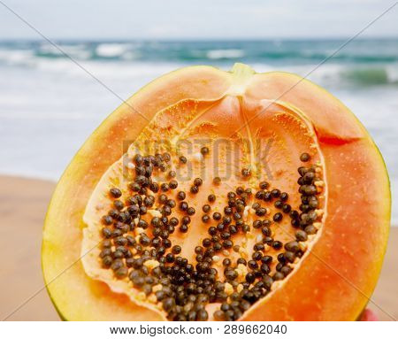 Ripe papaya cut in half on a beach