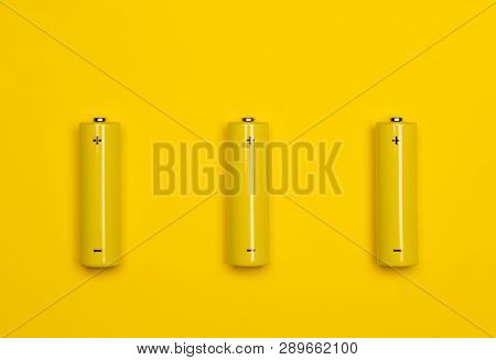 Top view of 3 yellow AA alkaline or rechargeable NiMH batteries on yellow background