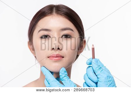 Surgery Concept. The Doctor Is Drawing A Pencil On The Patient's Face. The Patient Is Confident In T