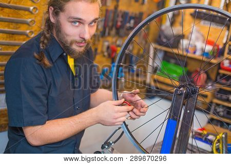 Blue Eyed Beraded Guy In Black Shirt Repairing Bicycle In The Workshop