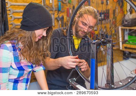 Handsome Beraded Guy And The Pretty Girl Repairing Bicycle In The Workshop Together
