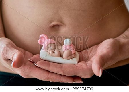 Pregnant Young Woomen Holds A Figurine Of Soap In The Shape Of A Newborn Baby Girl In Front Of Her B