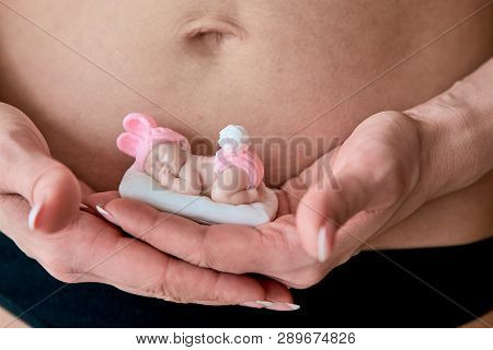 Pregnant Young Woomen Holds A Figurine Of Soap In The Shape Of A Newborn Baby Girl In Front Of Her B