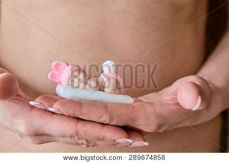 Pregnant Young Woomen Holds A Figurine Of Soap In The Shape Of A Newborn Baby Girl In Front Of Her B