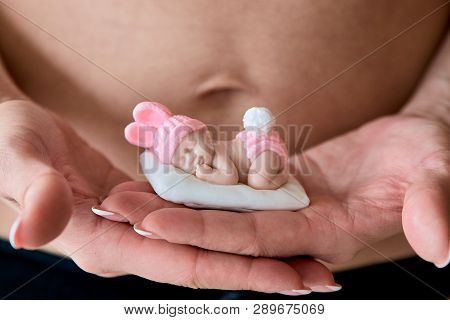 Pregnant Young Woomen Holds A Figurine Of Soap In The Shape Of A Newborn Baby Girl In Front Of Her B