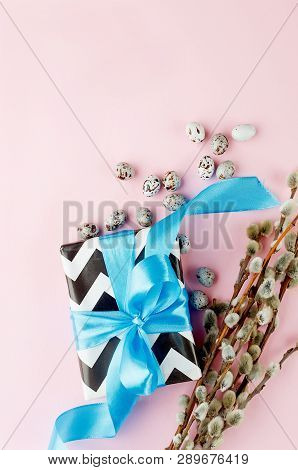 Gift With Blue Ribbon Small Easter Candy Eggs And Willow Twigs On Light Pink Background, Top View, C