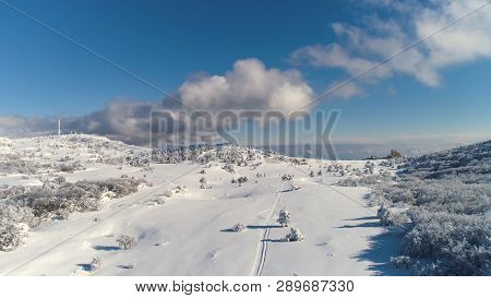 Aerial For The Snowy Countyside Road With Forest And Fields Surrounding. Shot. Rural Winter Area Wit