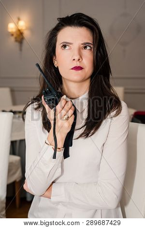 Young Woman In White Shirt Thougtfully Looking Up Holding The Transmitter In Her Hand On Blur Backgr