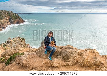 Woman, Girl With A Dog Sitting On The Shore Of The Atlantic Ocean