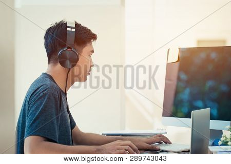 Student Learning Online Study Concept: Asian Young Man Listening With Headphones And Laptop, Sitting