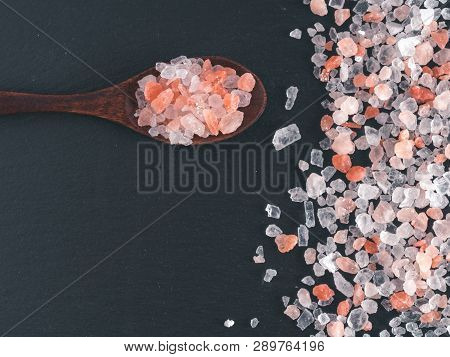 Himalayan Pink Salt In Spoon On Black Stone Background. Copy Space