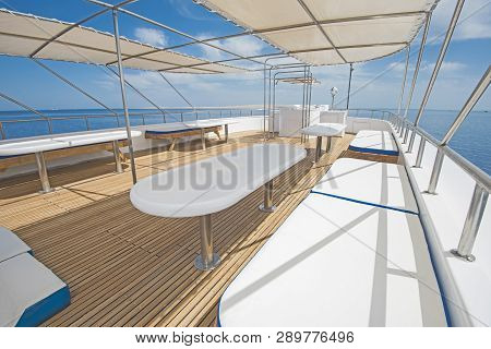 Sundeck Area Of A Large Luxury Motor Yacht With Chairs Sofa Table And Tropical Sea View Background