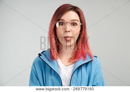 A Funny Girl In Glasses Makes Faces And Poses Her Face, Sticking Her Tongue Out. The Concept Of Friv